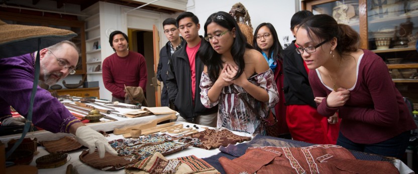 students peering over anthropology exhibit